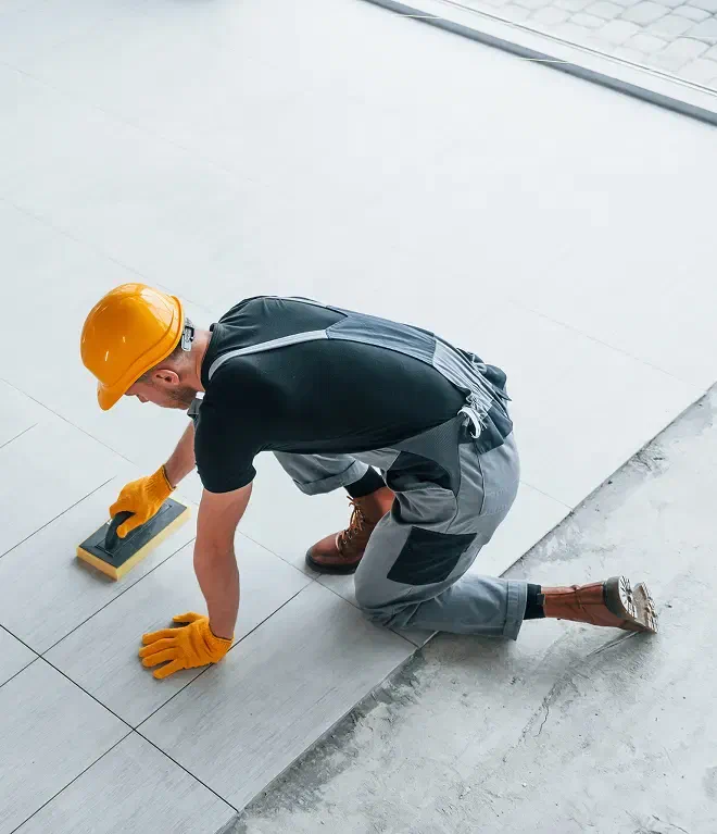 Instalador emboquillando piso cerámico con llana de hule